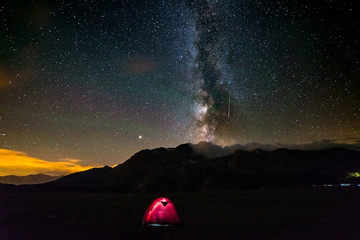 Wall Mural - camping under starry sky and milky way at high altitude on the alps. illuminated tent in the foregro