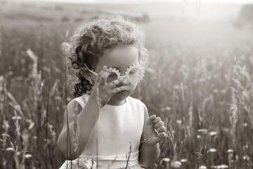 Little girl with curls in pink glasses in a field at sunset. A child in nature. Black and white photography