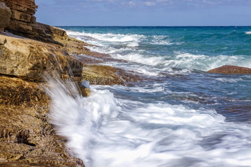 sunny day off on the Mediterranean coast of Crete, coastal beach area with the shore of Akmeaina; beautiful blue sea waters and white waves sloping towards the coast; beautiful blue sea waters and blu