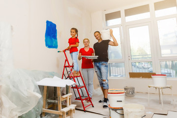 Wall Mural - Home makeover, decoration and painting: happy family smiling and posing, the girl is holding a paint roller