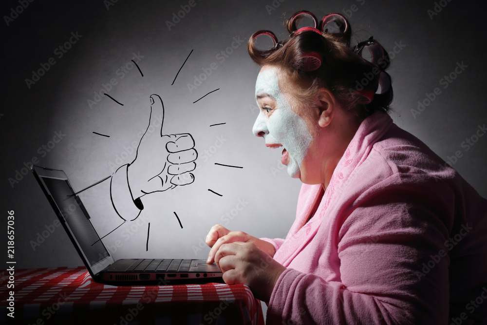 femme drôle avec bigoudis surfant son ordinateur portable avec dessin de pouce levé - obrazy, fototapety, plakaty 