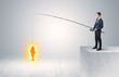 © ra2 studio - Young businessman fishing golden fish from the top of a building