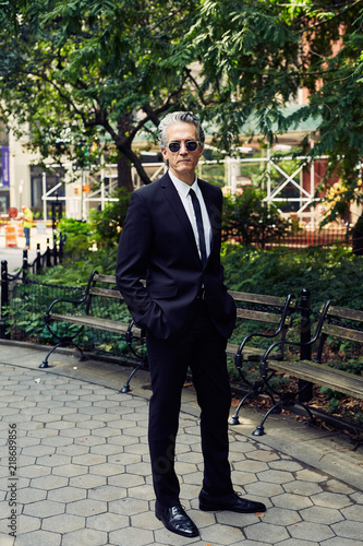 Grey Haired Caucasian Man Dressed In Contemporary Black Suit For