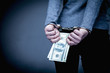 Woman handcuffed for her crimes with US Dollars in her hands as symbol of corruption and bribe