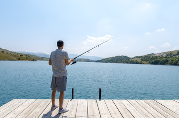 Back view man fishing on the lake, on sunny day 