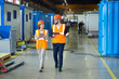 © Seventyfour - Full length  portrait of bearded businessman wearing hardhat talking to smiling  female factory worker while discussing production in workshop, copy space