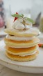 Close up to white plate with delicious pancakes topped by whipping cream and fresh strawberry