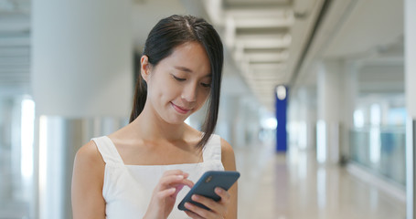 Poster - Woman holding cellphone with luggage in the airport