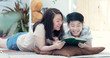 © sirikorn - Asian mother with son reading book together with smile face.