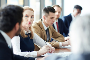 Wall Mural - Mature blond businesswoman talking to younger male colleague at political conference