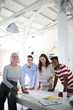 © pressmaster - Portrait of successful multiethnic business team standing around the table at modern office