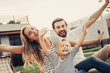 © Yakobchuk Olena - Portrait of beaming woman and cheerful male situating near satisfied child while gesticulating hands. Glad couple with daughter resting outside concept