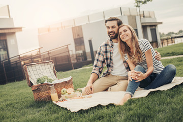 Wall Mural - Portrait of laughing unshaven boyfriend embracing outgoing female during conversation. They having lunch in open air. Glad couple having rest outdoor concept