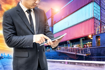 Wall Mural - Businessman using digital tablet checking scheduled ship standing in the container cargo ship