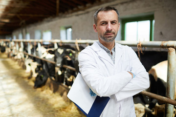 Young serious professional farmer in whitecoat crossing his arms on chest during work in kettlefarm