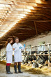 © pressmaster - Two contemporary farmers in whitecoats discussing new vaccine and cow virus during meeting in kettlefarm