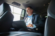 © opolja - Handsome businessman sitting with laptop on the backseat of the car