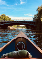 View over the bow of a wooden canoe looking out on a bridge crossing the river Alster in Hamburg on a beautiful summer day.