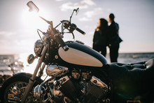 Selective Focus Of Classical Chopper Motorbike And Couple Looking At Sea On Background