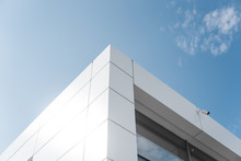 Building With White Aluminum Facade And Aluminum Panels Against Blue Sky.
