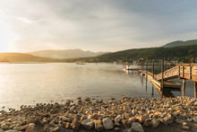 Scenic Bay At Sunset With A Wooden Pier And A Rochy Shore In Foreground. Port Moody, BC, Canada.