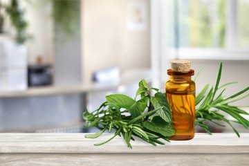 Wall Mural - Oil bottle and green herbs on blue background