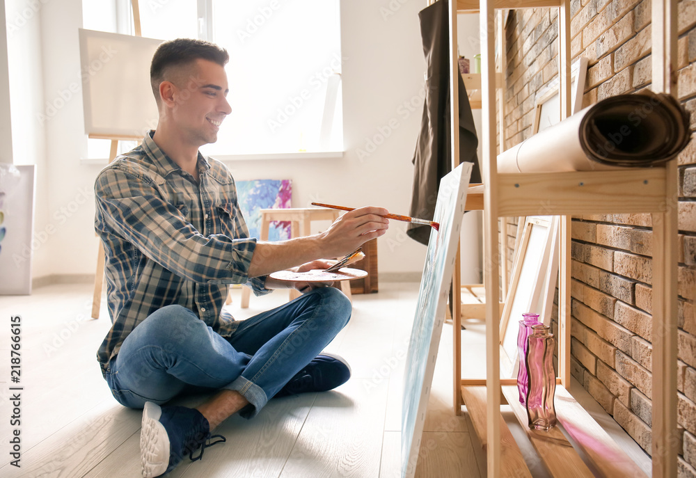 Male artist painting on canvas in workshop