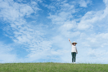 Wall Mural - Standing woman raised her hands on the mountain, natural green and beautiful sky.