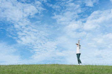 Wall Mural - Standing woman raised her hands on the mountain, natural green and beautiful sky.