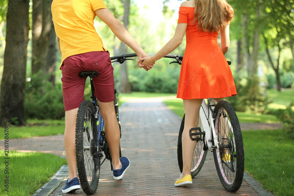 Young couple riding bicycles in park
