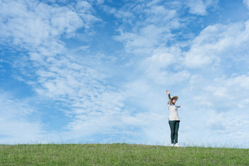 Wall Mural - Standing woman raised her hands on the mountain, natural green and beautiful sky.