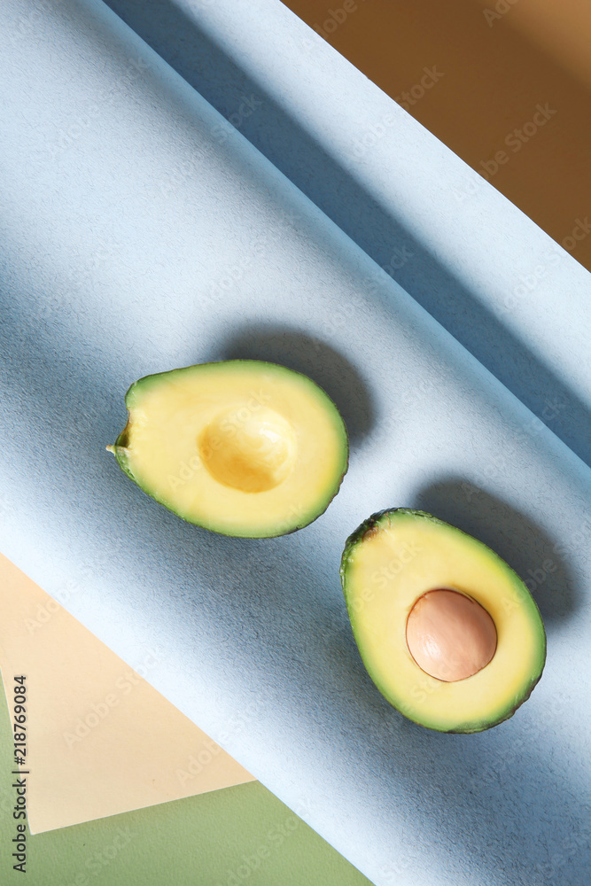 Halves of ripe avocado on color paper