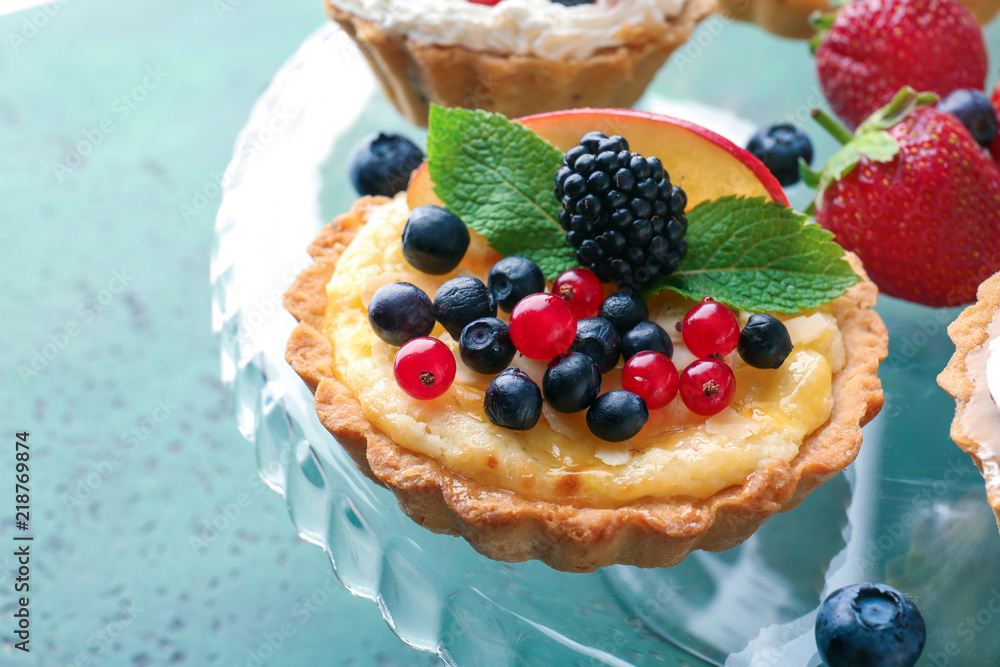 Tasty tartlets with berries on dessert stand, closeup