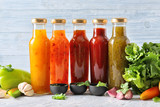 Bottles with different tasty sauces and vegetables on light table