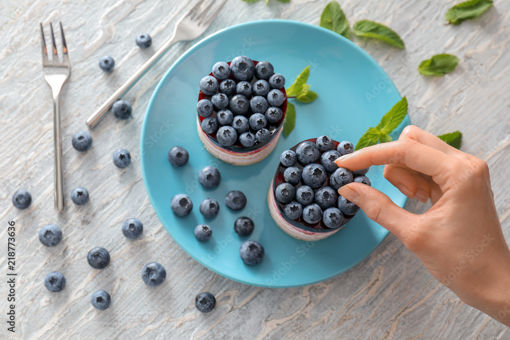Woman decorating dessert with blueberries on plate