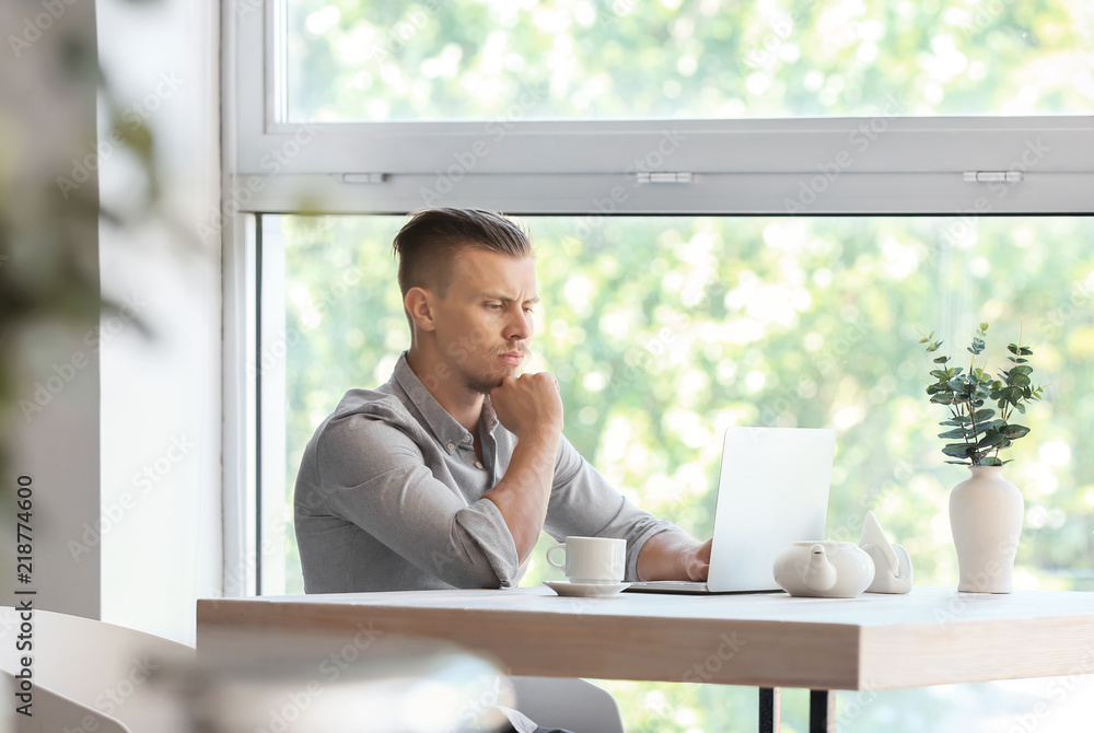 Troubled freelancer working on laptop in cafe