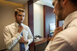 © opolja - People, business,fashion and clothing concept - close up of man in shirt dressing up and adjusting tie on neck at home.