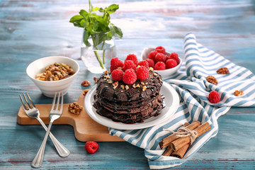 Composition with tasty chocolate pancakes and berries on wooden table