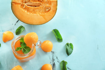 Mason jar with delicious smoothie and melon on table