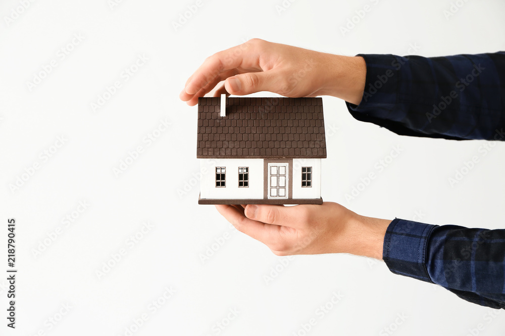 Man holding house model on light background