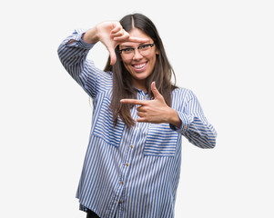 Wall Mural - Young beautiful hispanic business woman smiling making frame with hands and fingers with happy face. Creativity and photography concept.