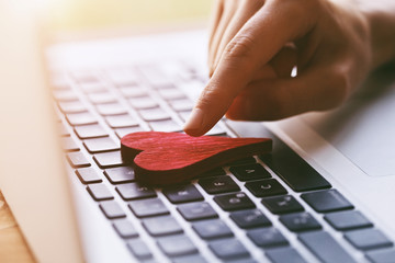 hand giving heart with laptop as like symbol in social media for posts and photos