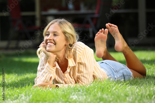 Hübsche junge Frau liegt lachend und barfuß im Gras Stock Photo | Adobe