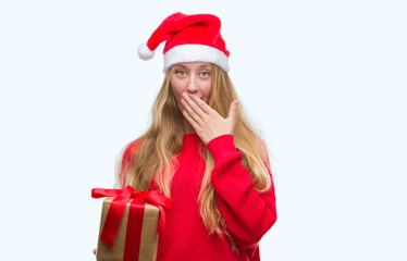 Sticker - Blonde teenager woman wearing santa claus hat cover mouth with hand shocked with shame for mistake, expression of fear, scared in silence, secret concept