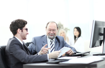 two businessmen discussing work issues sitting at their desk