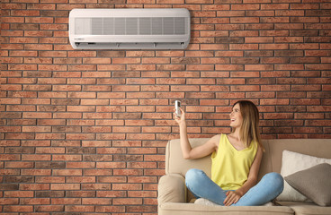 Canvas Print - Woman with air conditioner remote at home