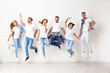© New Africa - Group of young people in jeans jumping near light wall