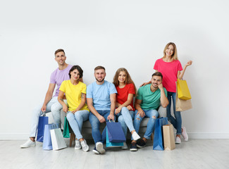 Poster - Group of young people with shopping bags sitting on sofa near light wall