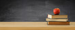 © tomertu - back to school banner. stack of books over wooden desk in front of blackboard.
