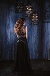 © cherry_d - Young woman with long curly hair and makeup in evening long luxury dress, posing in a dark interior room. fashion beauty portrait
